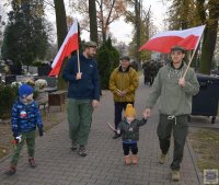 dwóch mężczyzn idących z dwójką dzieci trzymając flagę Polski
