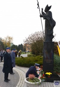 komendant kluczborskiej policji w obecności innych dowódców służb mundurowych składając kwiaty pod pomnikiem św. Jana Pawła II , przy kościele w Kluczborku